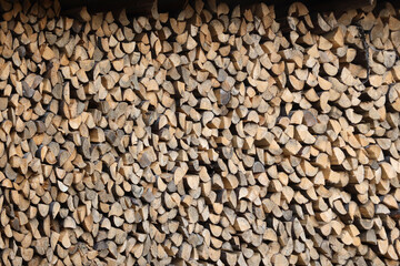 Firewood stacked near the wooden wall of old hut. Many chopped logs of firewood close up