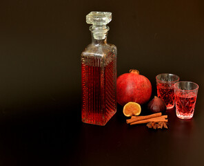 Fig-pomegranate liqueur, strong homemade alcohol with cinnamon, anise in two glasses and a crystal...