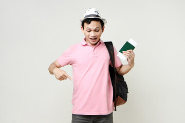 Asian man backpacker holding passport and airline ticket. pointing finger. digital nomad and travelling concept. on isolated background
