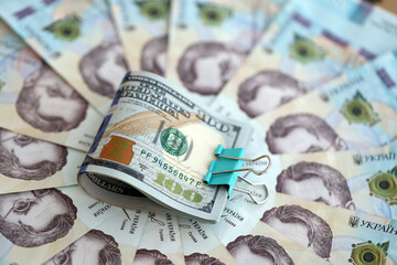 Bunch of hundred US dollar bills lies on many banknotes of ukrainian hryvnias. Economical default,...