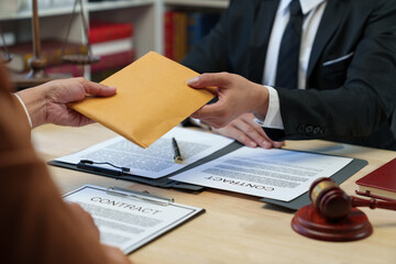 The hand of a corrupt businesswoman or politician is offering a bribe to a lawyer in the form of a...