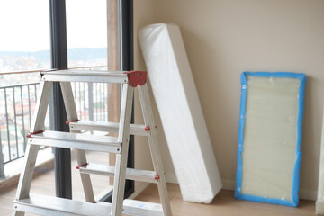Metal ladder standing in empty room, renovation and improvement concept.