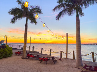 A tropical restaurant party area along the ocean bay water in Tampa Florida. This area is ideal for open air party spaces with beautiful sunrises and a pretty travel destination in Florida summertime. - obrazy, fototapety, plakaty