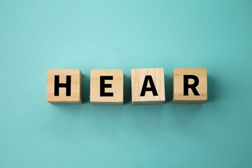 wooden cube with the word hear. the concept of hearing or being heard