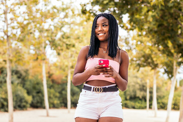 Portrait of an African American woman using smartphone a park in summer