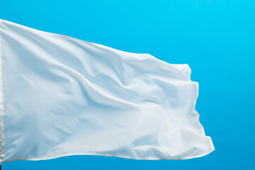 White flag waving on blue background - obrazy, fototapety, plakaty