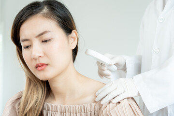 skin problem and beauty of asian girl. Dermatologist use magnifying glass look itchy skin from skin allergic, steroid allergy, sensitive skin, chemical allergy, rash, insect bites, Dermatitis.