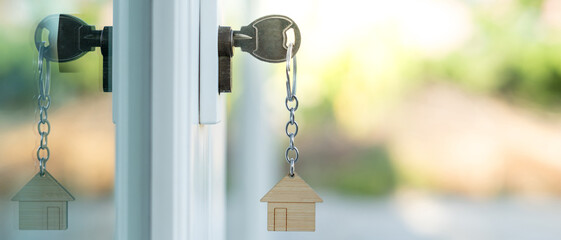 Landlord key for unlocking house is plugged into the door. Second hand house for rent and sale. keychain is blowing in the wind. mortgage for new home, buy, sell, renovate, investment, owner, estate - obrazy, fototapety, plakaty