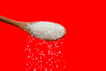 Sugar crystals falling out of wooden spoon