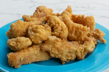 Delicious crispy fried chicken breast strips on blue plate, easy recipe for outdoor picnic or party, closeup