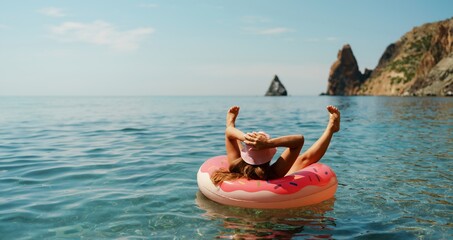 Summer vacation woman in hat floats on an inflatable donut mattress. Happy woman relaxing and...
