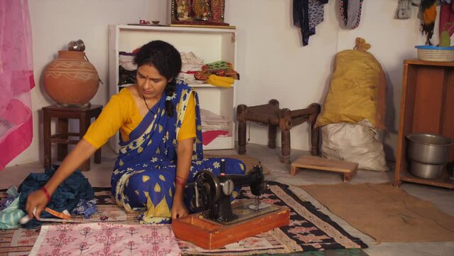 A middle-aged woman is taking the measurements - inch tape  measuring tape. A village lady / a dressmaker is at work at home - a tailor  an occupation  a rural household  an independent woman  a bu...