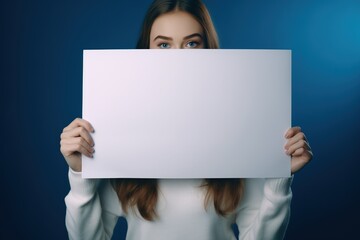 Naklejka premium Cute little girl holding blank white sheet of paper in her hands