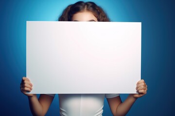 Cute little girl holding blank white sheet of paper in her hands