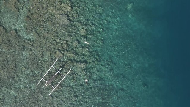 Tourists swim in clear shallow water over coral reef in Bali Indonesia