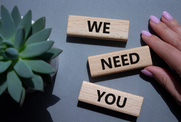 We need You symbol. Wooden blocks with words We need you. Beautiful grey background with succulent...