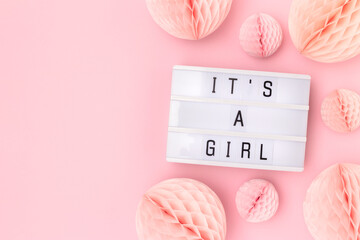 It's a girl. Lightbox with letters and tissue paper balls in a pink color. Baby shower composition with copy space. - obrazy, fototapety, plakaty