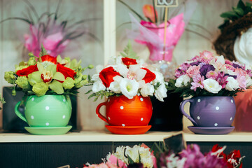 Three colorful flowerpots Sitting on a Store Shelf . Image in a boutique of clay pots with floral arrangements
