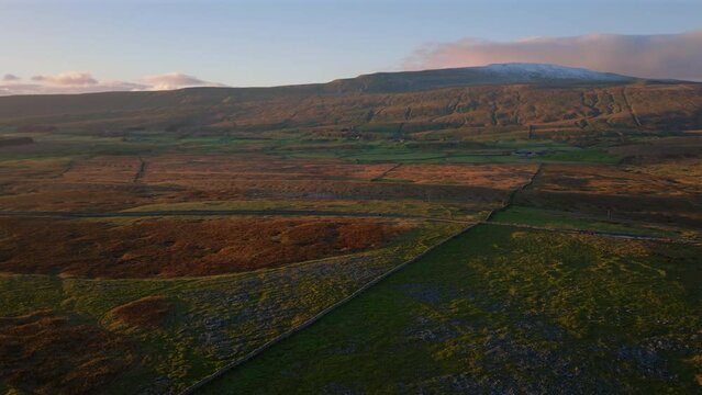 Establishing Aerial Drone Shot of Snowy Whernside Mountain at Golden Hour Sunset in Yorkshire Dales UK