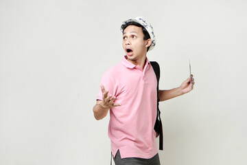 Asian man backpacker holding passport and airline ticket with shocked and surprised expression....