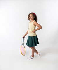 Studio portrait confident standing young girl n green skirt and yellow tank top holding tennis racket  - 696714075