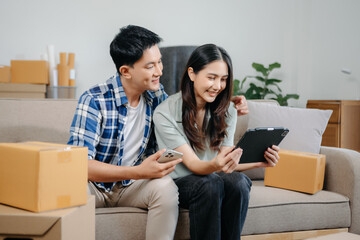Obraz premium Happy asian young attractive couple man and woman with big boxes moving into a new house, new apartment for couple the new home, Moving house. on sofa.