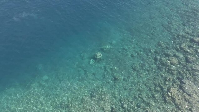 Bird's eye view of clear ocean water near shore, reef drops into deep