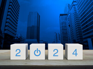 2024 start up business icon on white block cubes on wooden table over modern office city tower and...