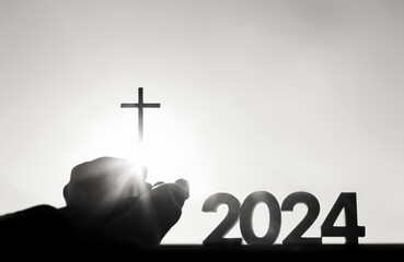 New Year 2024 Christians hold high the cross of Jesus Christ, symbolizing death and resurrection
 - obrazy, fototapety, plakaty