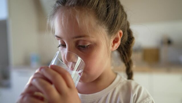 Girl drinks water in kitchen at home. Child drinking refreshing water. Healthy lifestyle quenching thirst. Active girl drinks water. Combat dehydration good health. Problem of environmental pollution
