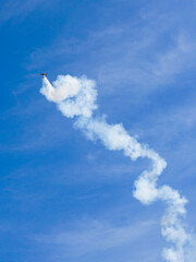 Aerobatic plane performing a multiple corkscrew maneuver leaving a smoke trail