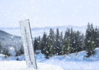 Weather thermometer under falling snow outdoors on winter day, space for text