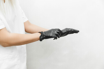 The cosmetologist puts on sterile black gloves and prepares to receive clients.