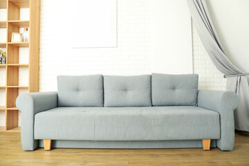 Gray sofa with wooden shelves on the background