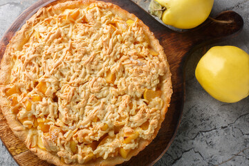Autumn fragrant crust quince pie tart close-up on a wooden board on the table. Horizontal top view from above