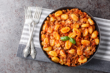Homemade delicious gnocchi bolognese close-up on the plate on the table. Horizontal top view from above