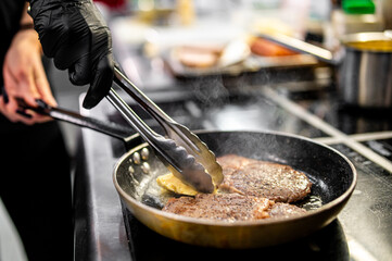 Professional chef cooking beef steak in frying pan on stove in restaurant kitchen