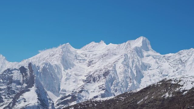 4K Landscape shot of snow covered Himalayan mountain peaks during the winter season as seen from Keylong at Lahaul Valley in Himachal Pradesh, India. Snowy mountain peaks during the winter season.