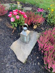 Geschm&uuml;cktes Grab auf dem Friedhof im Herbst mit Blumen und Laterne