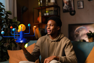 Black dark skinned African American blogger guy in the photo captures the attention of his subscribers and inspires them to learn more about the cosmos.