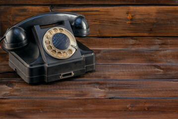 Retro style rotary phone on the wooden table close up background with copy space. Front view.
