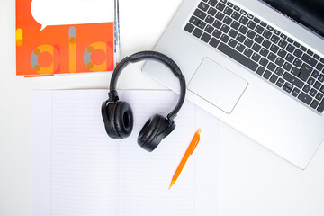 Top view of a laptop, headphones and a notebook on white background