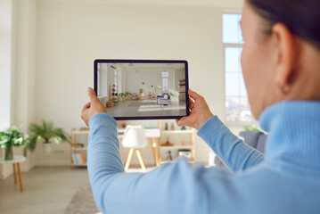 Woman takes photograph of large renovated home interior. Property owner or estate agent uses wide angle camera on smart tablet to take photo or give walkthrough video tour about new apartment for sale - obrazy, fototapety, plakaty
