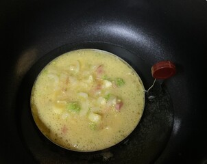 cooking of vegetables ham omelet in black pan, pancake