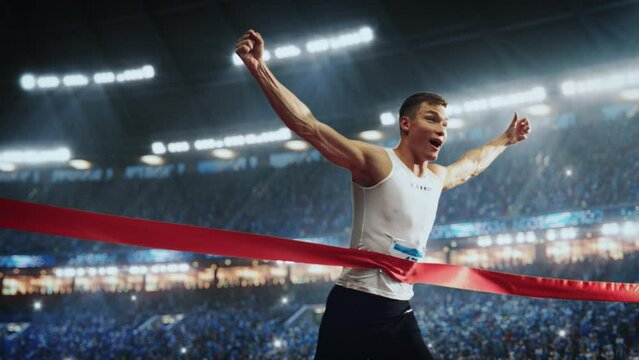 Strong Athlete is Performing at His Limit, Finishing a Competitive Run, Crossing the Finish Line with a Red Ribbon. Cinematic Sports Footage at a Crowded Arena with Spectators. Super Slow Motion
