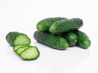 Fresh cucumbers of which one is sliced ​​isolated on a white