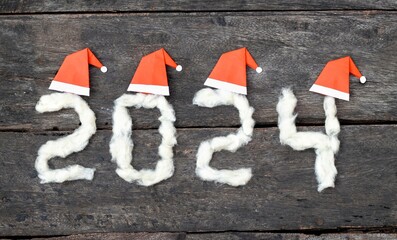 2024 New Year Concept with Cotton and Merry Christmas Santa Claus Hats on Wooden Background, Happy...