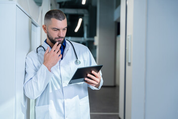 Charismatic and attentive doctor is seen carefully studying a patient's medical history on a...