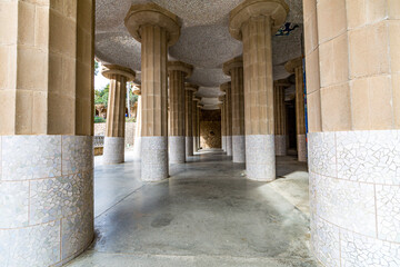 Front perspective of hall with columns with fragments of tiles and ceiling with small domes, Hypostyle room in Park Güell by Antoni Gaudí, sightseeing day in Barcelona, Catalonia Spain