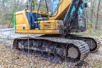 Partial view of a grab excavator covered in mud, track caterpillar crampon wheel, muddy ground at a...